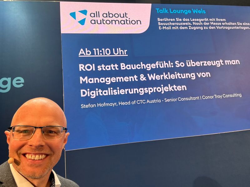 Stefan Hofmayr vor der Vortragsleinwand „ROI statt Bauchgefühl“ in der Talk Lounge der Messe all about automation in Wels